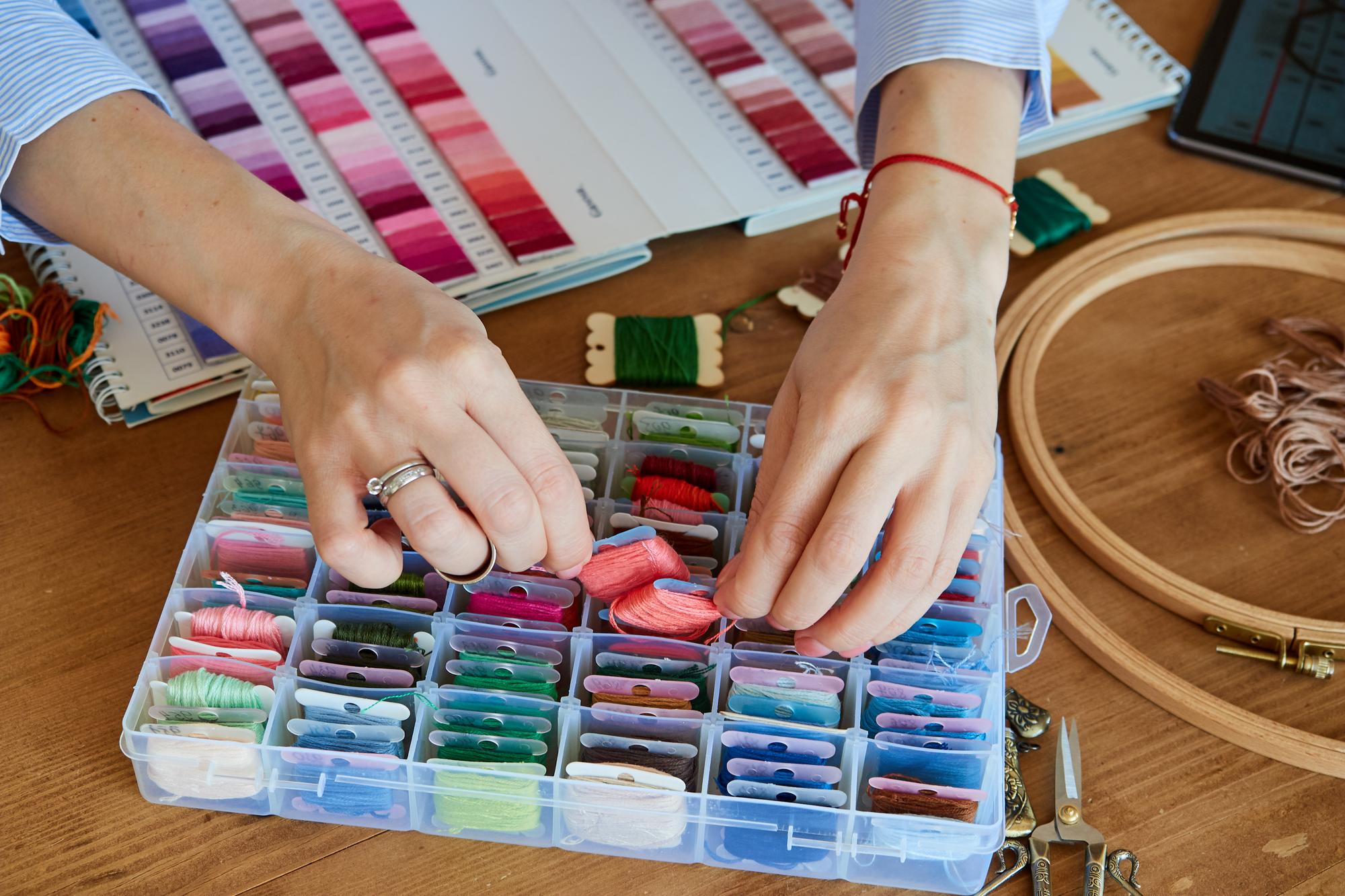 hands arranging embroidered sample on table